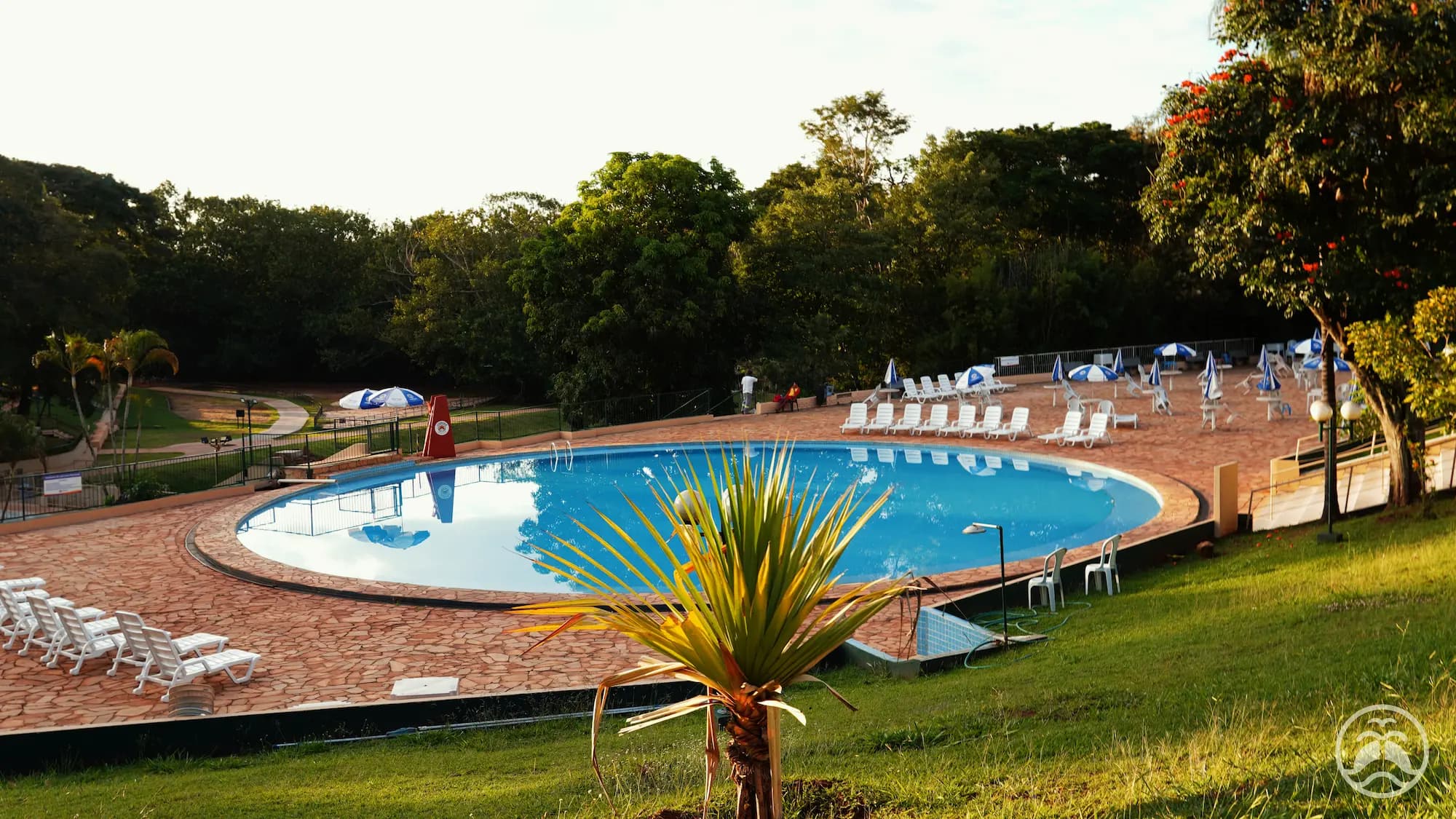 Piscina redonda do clube com deck de pedra e espreguiçadeiras ao redor